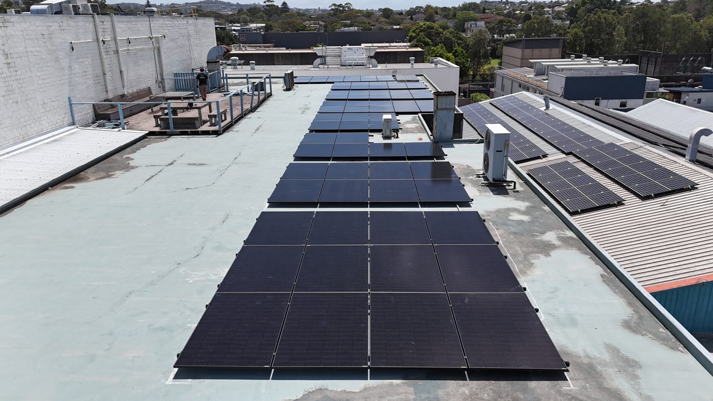 Aerial view of a commercial rooftop solar array with hills in the background