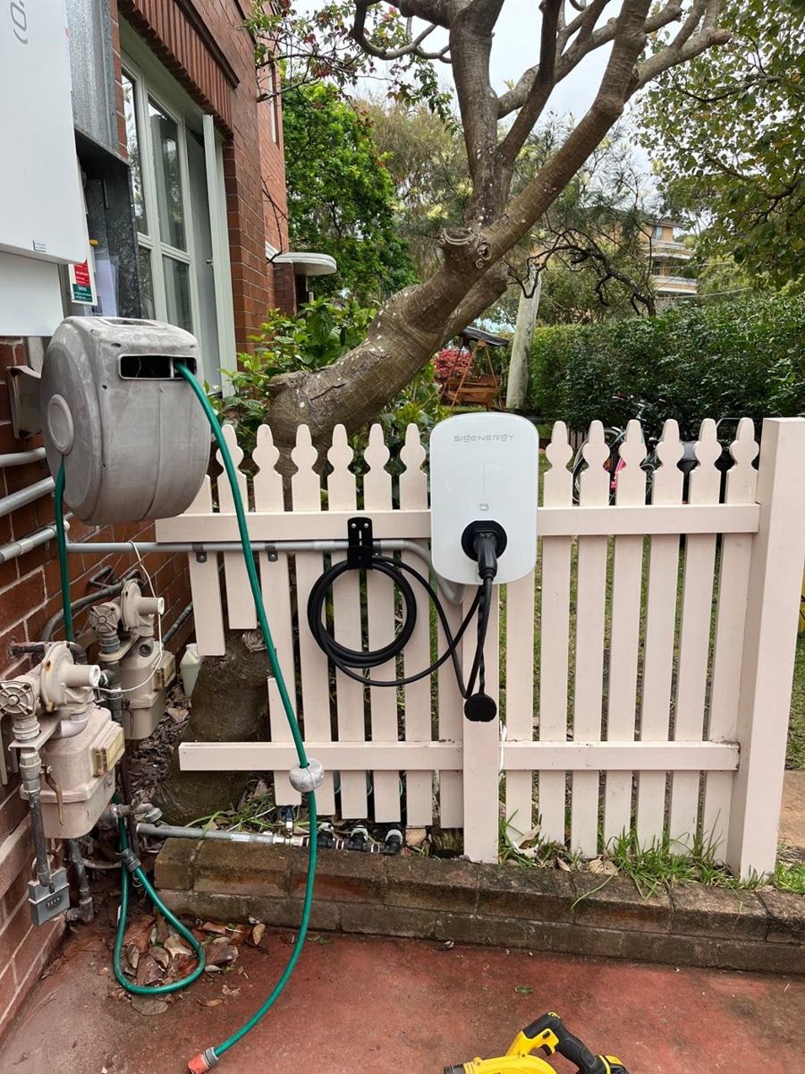EV charger installed on a garden fence beside the house