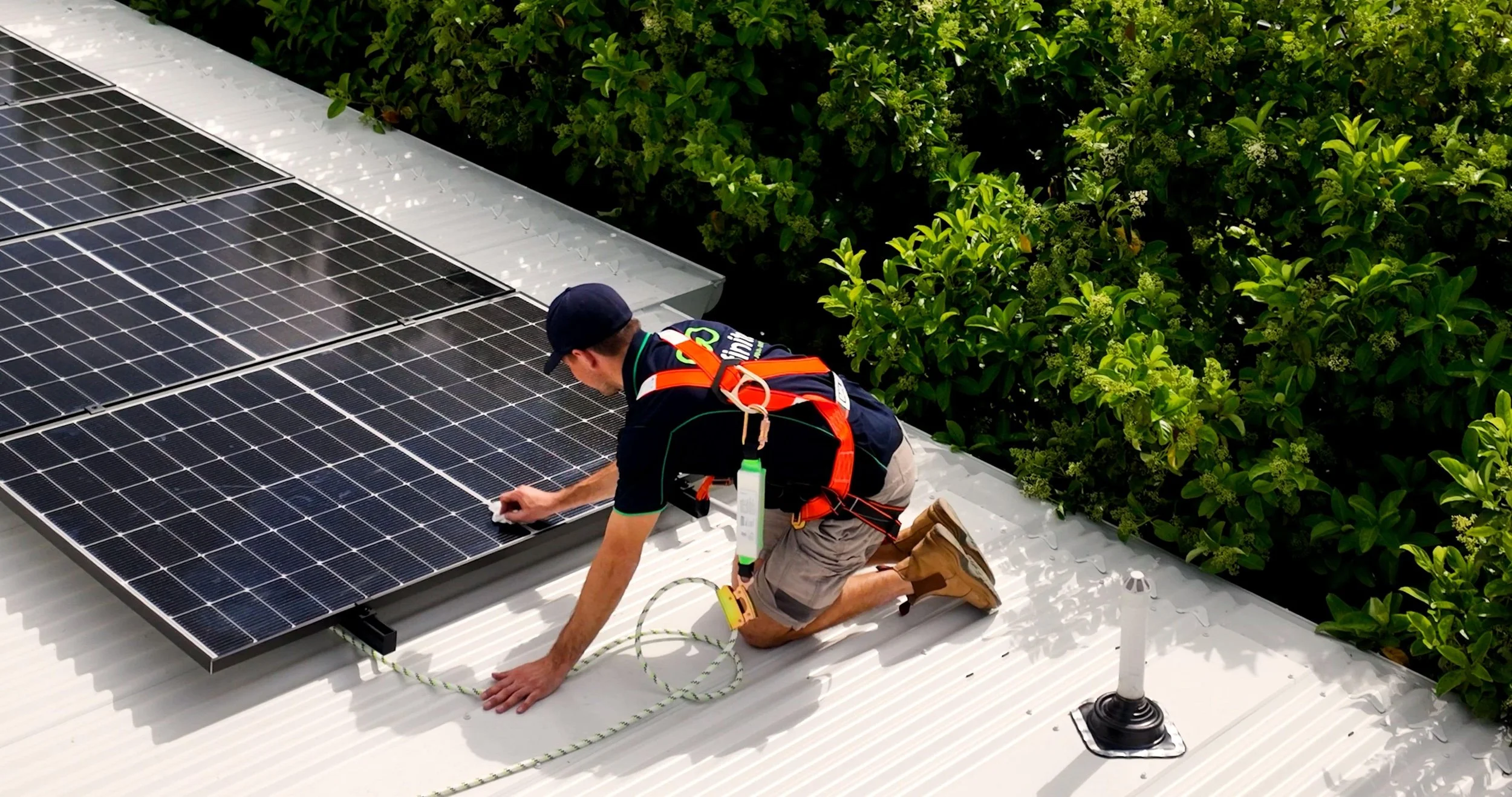 Infinite installer kneeling on a roof installing solar panels
