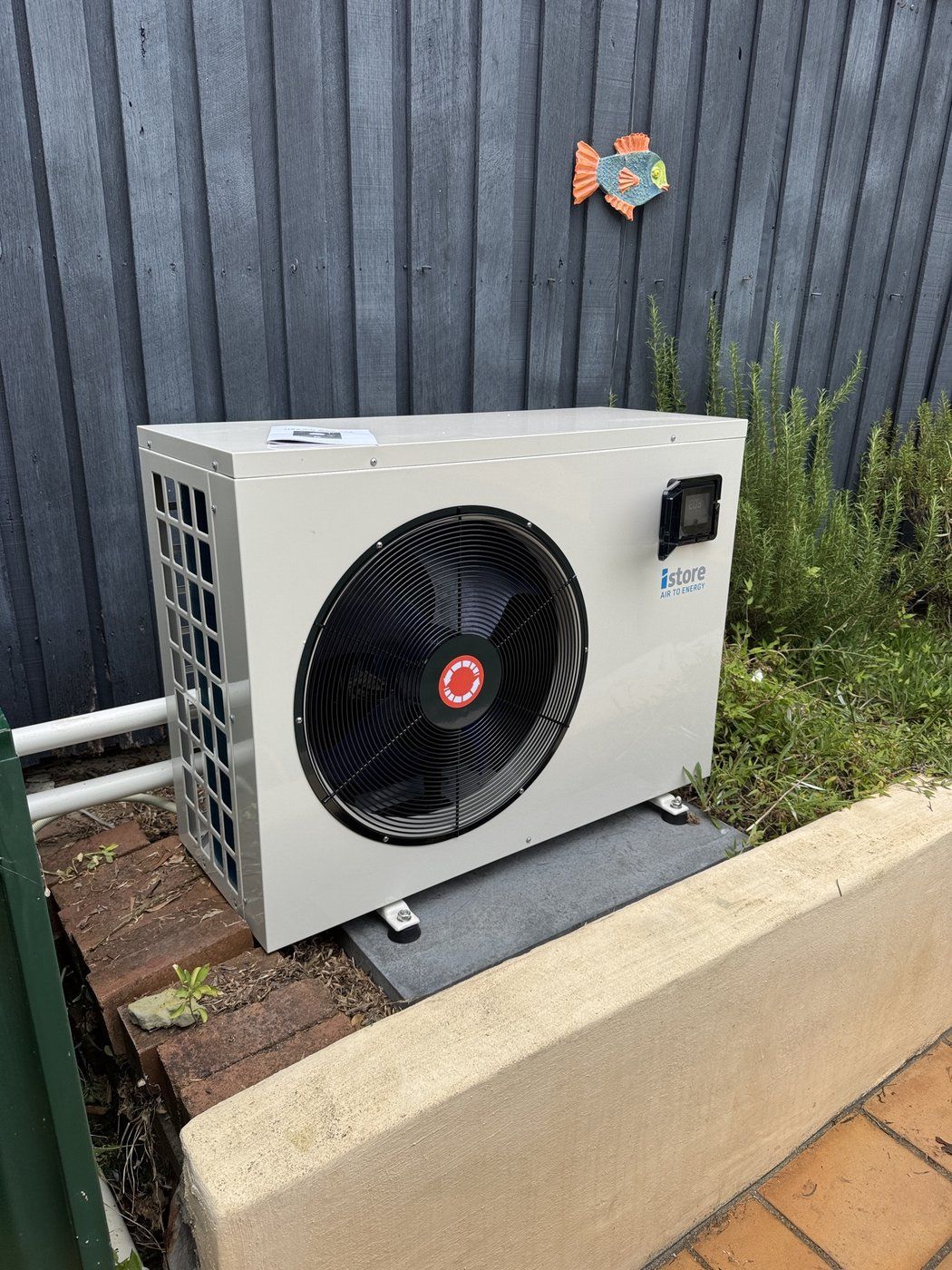 iStore pool heat pump unit installed against a timber fence at a different job
